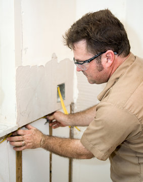 Electrician installing wiring in an insulated wall.