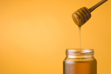 Honey falling from a dipper into a jar