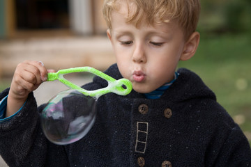 little boy blows soap bubbles in the autumn