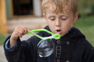 little boy blows soap bubbles in the autumn