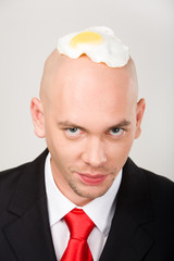 Bald man with fried eggs on top of head looking at camera