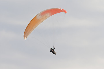 A man with a colorful paraglider flying in the sky