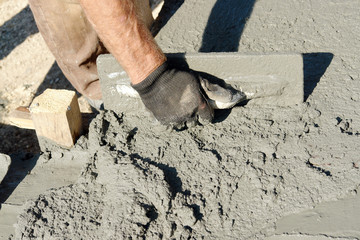 Closeup of mason's hand spreading concrete mix