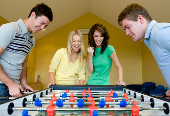 Four friends playing table football at home