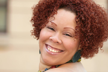 female with short curly red hair and bright jewelry