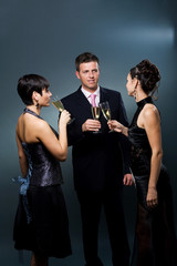 Three people drinking champagne on a party.