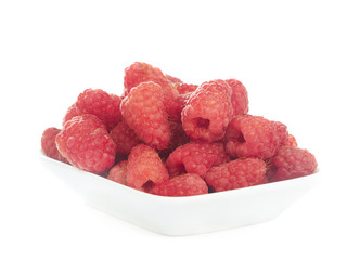 Several ripe raspberries at small plate isolated on white