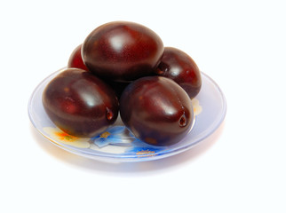The ripe plums lying on a plate