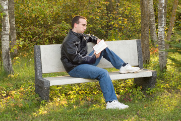 A young caucasian man sitting on a park bench