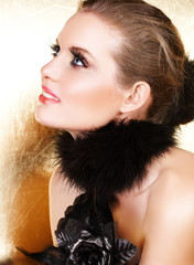 Blond woman with long false lashes in black glove and feather