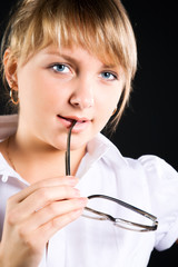 Young businesswoman with eyeglasses. On dark background.