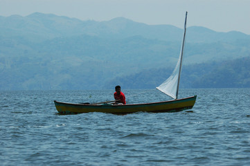 A fisher with his boat sailing near coast