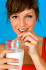 Portrait, Junge attractive Frau mit Milch vor blauem Hintergrund