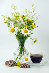 cup with coffee, cookies and bunch of flowers