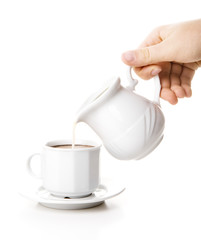 Hand pours milk in coffee