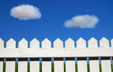 White picket fence, green grass and sky