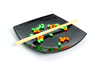 chemical diet - colored pills on black plate and chopsticks
