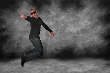 Fototapeta na wymiar African American Man Jumping on Grunge Studio Backdrop