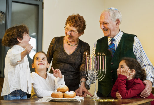 grandperents and grandchildren lightening Hanukkiyah together