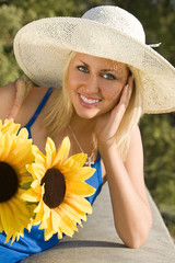 A beautiful young blond woman carrying a basket of sunflowers