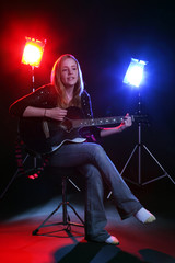 woman with guitar on stage with red and blue concert lights
