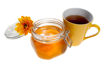 Tea cup and a honey jar, with a flower on it, isolated