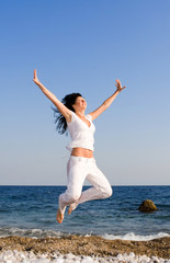Obraz premium happy young woman is jumping in the beach