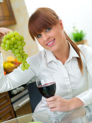 Beautiful woman in kitchen drinking red wine