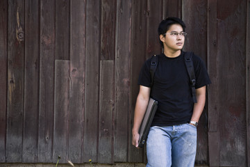 Obraz premium An asian student carrying a laptop and a backpack