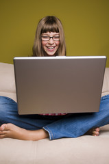 Young girl relaxing with laptop on a couch.
