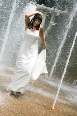 Beautiful young bride playing in a waterfall on her wedding day.