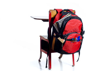A red, vintage school desk with a red backpack overflowing