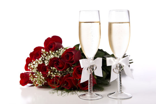 A bouquet of red roses and two champagne flutes