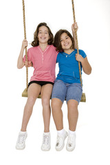 Caucasian sisters playing on a swing on white background