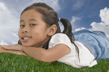 young Asian child laying down outdoors and looking at camera
