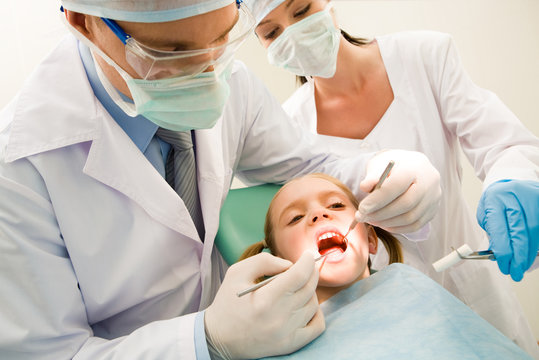 Image of dental checkup being given to little girl by dentist