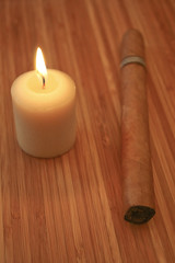 Close up of cigar and candle on wooden table