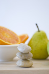 zen stones and orange, apple, pear fruits on background