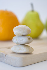 zen stones and orange, apple, pear fruits on background
