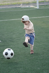 Obraz premium The kid hazardously playing football in stadium