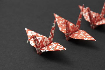 Three origami cranes on a black ground