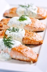 Fotobehang Cooked salmon fillets with dill sauce on white plate © Elenathewise