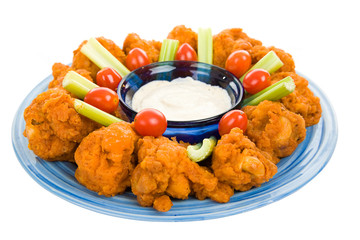 Spicy buffalo wings on platter with celery and dip.  Isolated