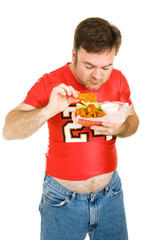 Overweight middle aged man eating greasy chicken wings.