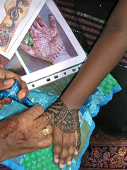 Henna tattoo artist crafting a hand with elaborate patterns