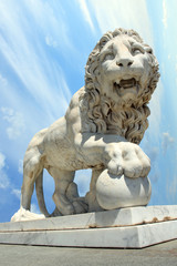 Fototapeta na wymiar lion statue with ball over cloudy sky