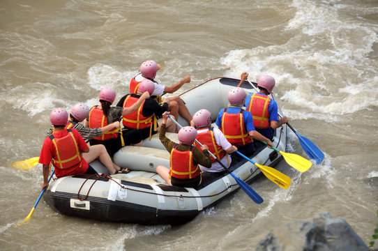 Group of tourists rafting down a  mountain river in a boat.