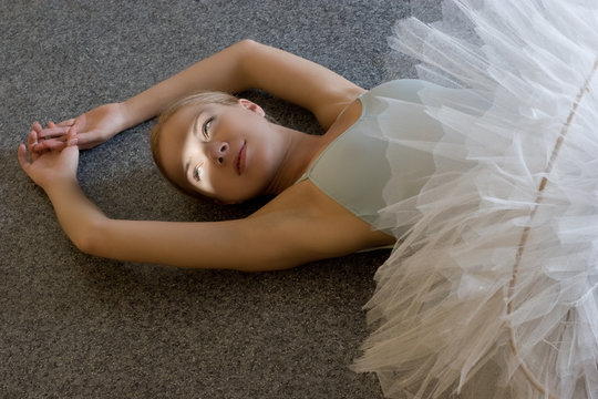 smiling ballerina is relaxing on the floor