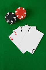 Four aces with poker chips on green poker table.