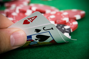 Ace of hearts and black jack with poker chips in the background.